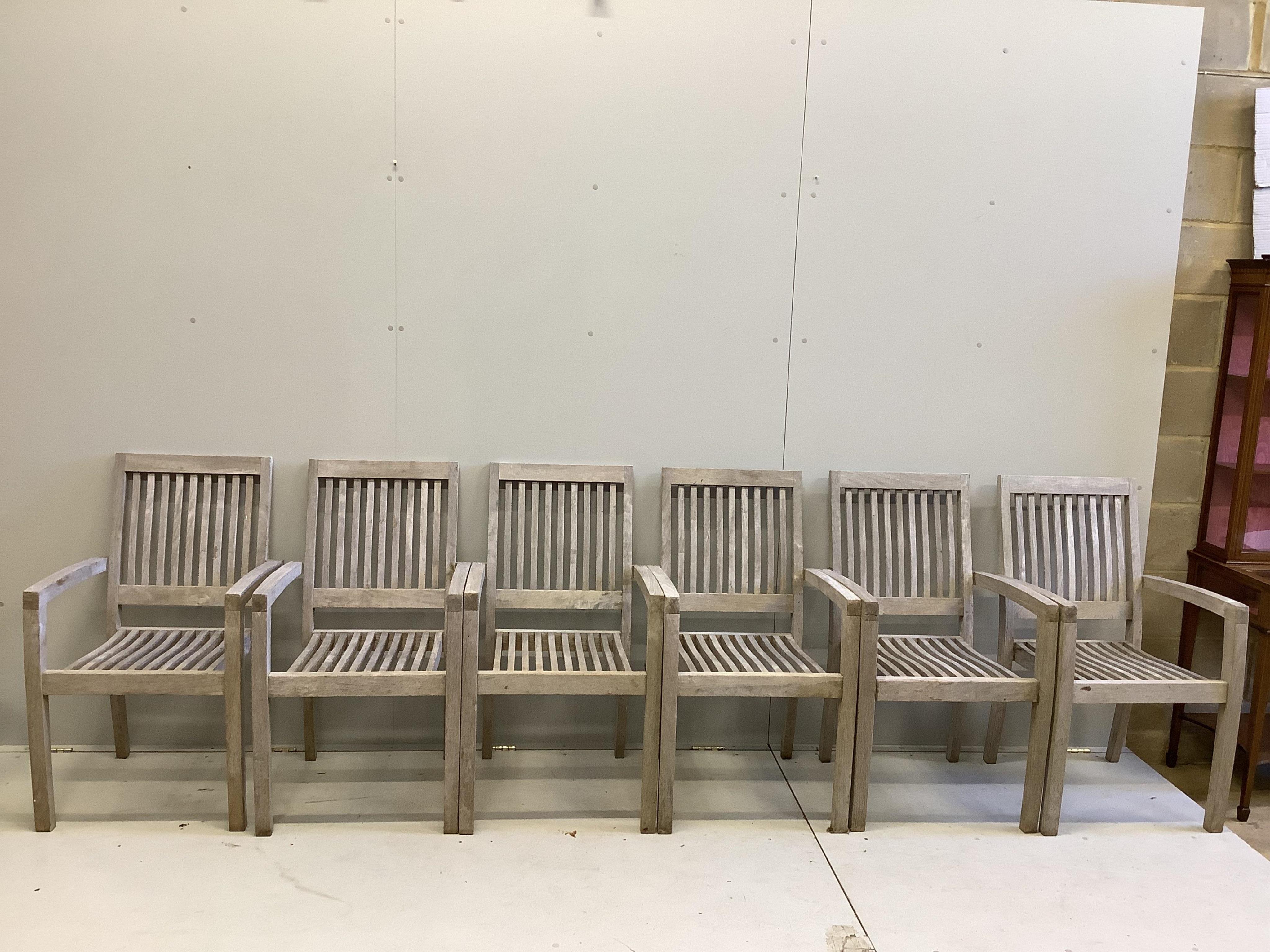 A weathered circular teak garden table and a set of six matching armchairs. Condition - fair